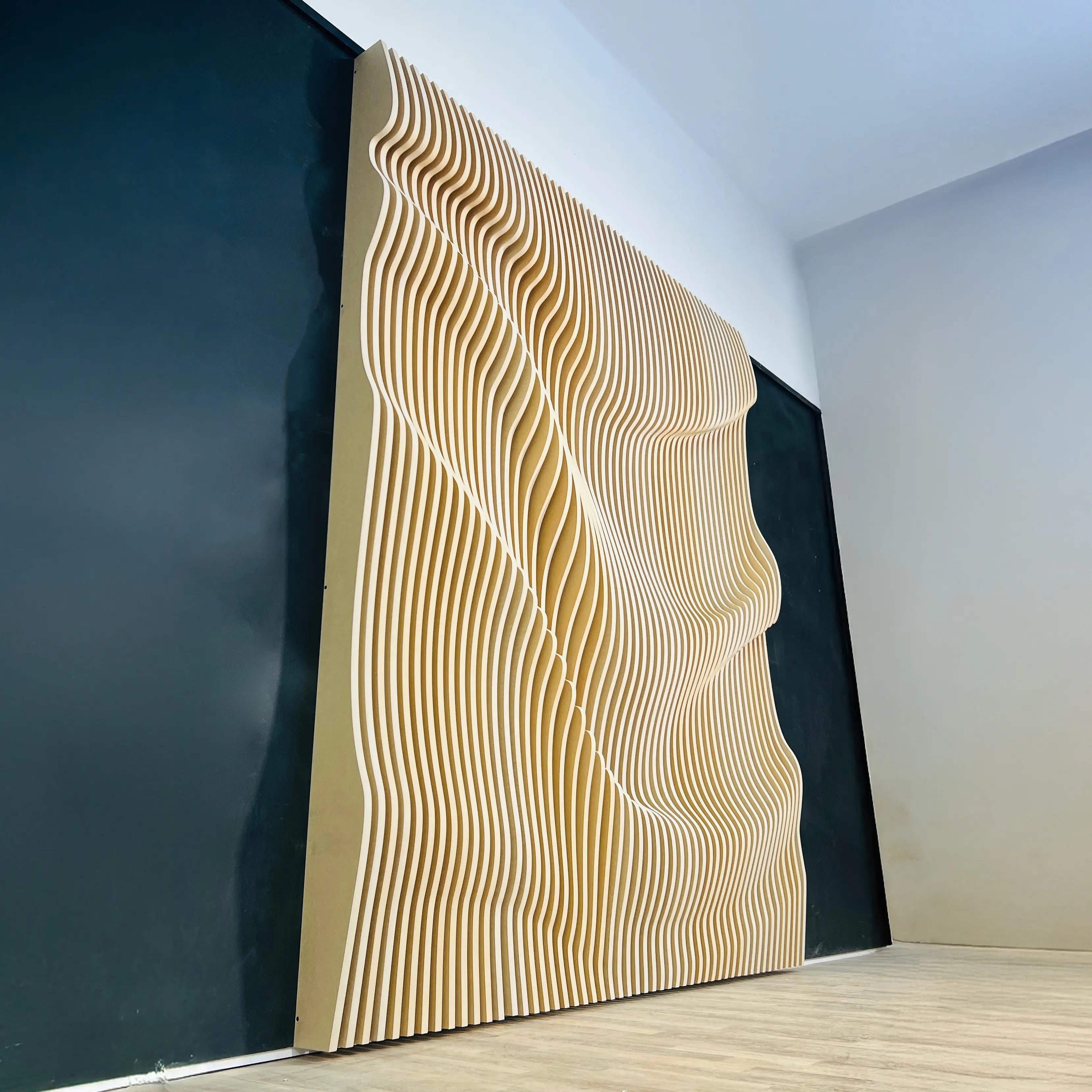 Wall with wavy wooden panel design in a room with black and white walls.